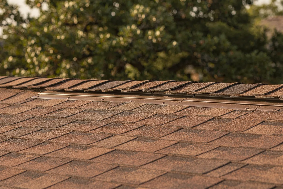 A ridge vent along the peak of a finished brown shingle roof